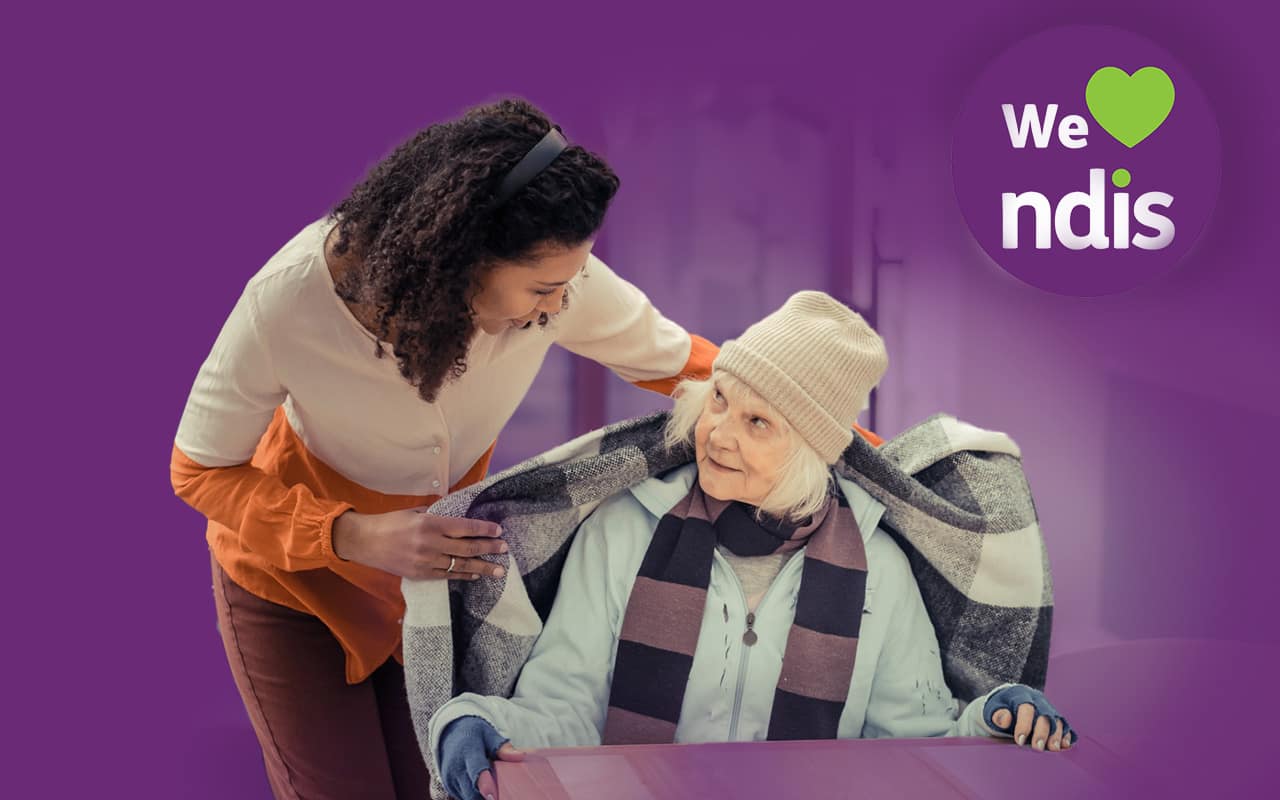 A disability support worker helping a participant use a tablet, representing the benefits of a custom NDIS website